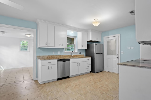 kitchen featuring light stone countertops, appliances with stainless steel finishes, a sink, white cabinetry, and visible vents