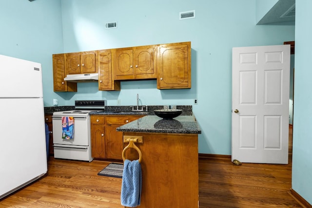 209 Jungle Rd, Edisto Beach, SC 29438 - kitchen featuring white appliances, under cabinet range hood, a high ceiling, brown cabinets, and wood finished floors