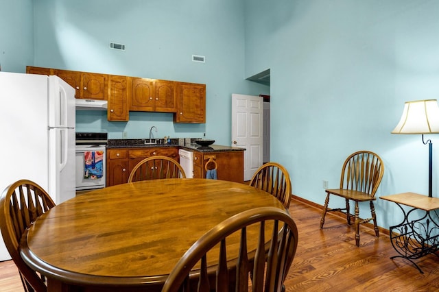 209 Jungle Rd, Edisto Beach, SC 29438 - kitchen with white appliances, a towering ceiling, a sink, dark countertops, and under cabinet range hood