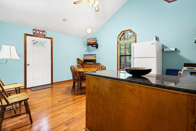 209 Jungle Rd, Edisto Beach, SC 29438 - kitchen featuring freestanding refrigerator, a ceiling fan, light wood-style flooring, dark stone counters, and vaulted ceiling