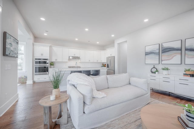 living room with baseboards, wood finished floors, and recessed lighting