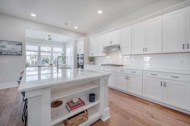 kitchen with tasteful backsplash, open shelves, a sink, appliances with stainless steel finishes, and under cabinet range hood