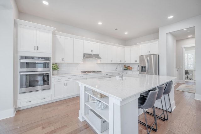 kitchen featuring white cabinets, appliances with stainless steel finishes, under cabinet range hood, and a sink
