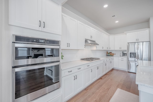 kitchen featuring under cabinet range hood, white cabinets, appliances with stainless steel finishes, and light wood-style floors
