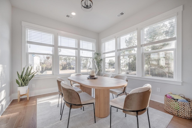 sunroom featuring baseboards, wood finished floors, and visible vents
