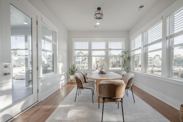 sunroom / solarium with baseboards, wood finished floors, and visible vents