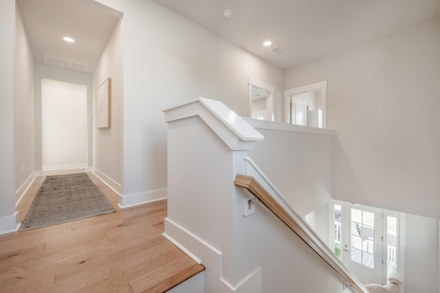 hall featuring visible vents, baseboards, recessed lighting, an upstairs landing, and wood finished floors