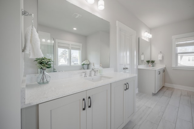 bathroom featuring two vanities, a sink, and baseboards