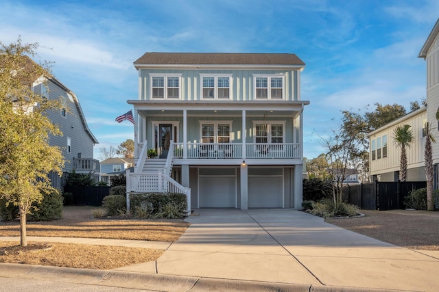 coastal home with a porch, concrete driveway, a garage, stairs, and board and batten siding
