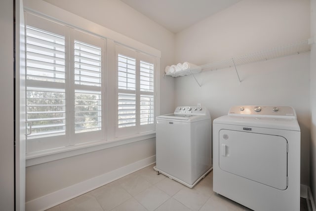 washroom with light tile patterned flooring, baseboards, laundry area, and separate washer and dryer
