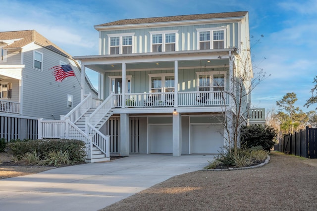 raised beach house featuring stairway, board and batten siding, an attached garage, driveway, and covered porch