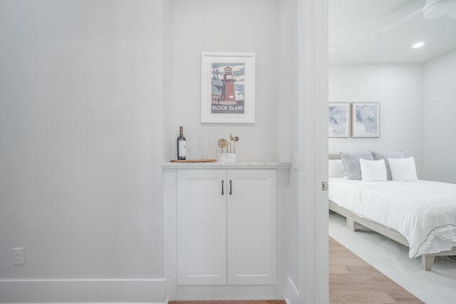 bedroom featuring bar area and light wood-style floors