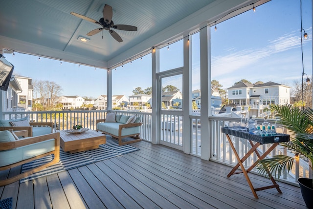 sunroom / solarium with a ceiling fan, a residential view, and plenty of natural light