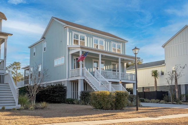 coastal inspired home with board and batten siding, stairs, and covered porch