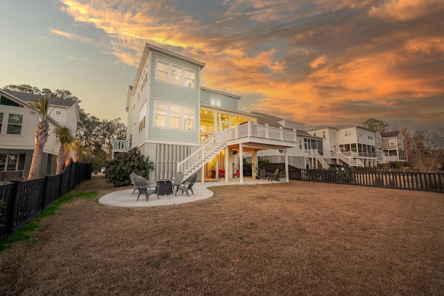 back of house with stairway, a patio area, a lawn, a fire pit, and a fenced backyard