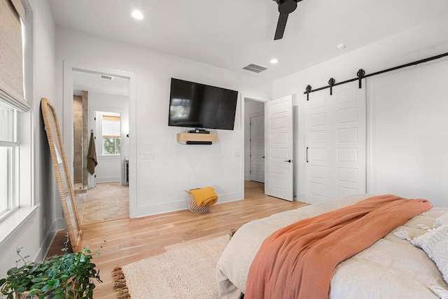 bedroom featuring a barn door, recessed lighting, visible vents, and light wood-type flooring