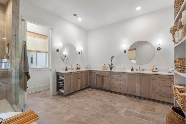 bathroom featuring double vanity, a stall shower, visible vents, and a sink