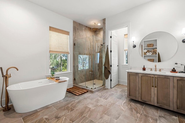 bathroom featuring vanity, a shower stall, a freestanding tub, and baseboards