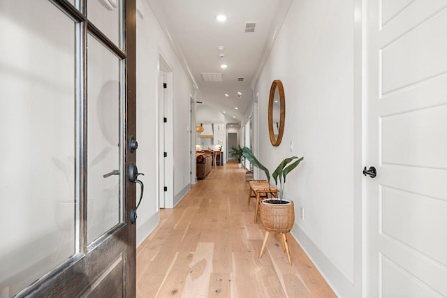 hallway with light wood finished floors, visible vents, baseboards, ornamental molding, and recessed lighting