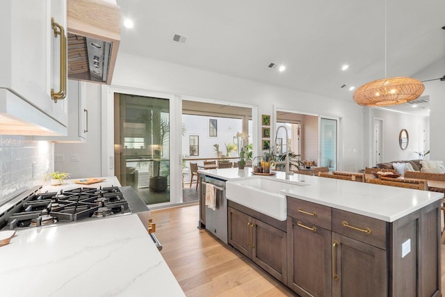 kitchen featuring a sink, a wealth of natural light, dark brown cabinets, appliances with stainless steel finishes, and backsplash