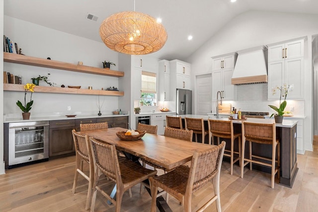 dining area featuring visible vents, high vaulted ceiling, light wood-style flooring, recessed lighting, and wine cooler