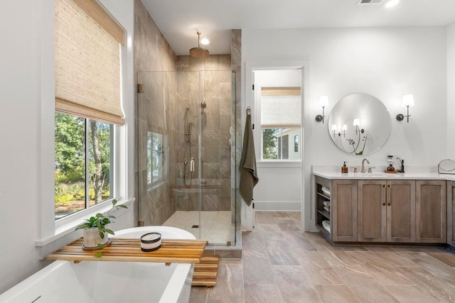 bathroom with a healthy amount of sunlight, a freestanding bath, vanity, and a shower stall