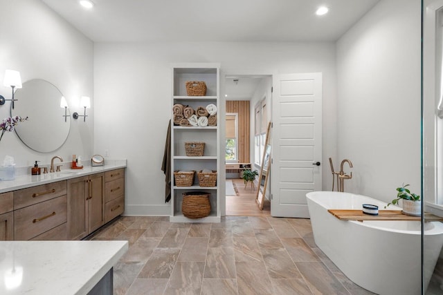 bathroom with recessed lighting, a freestanding tub, baseboards, and vanity