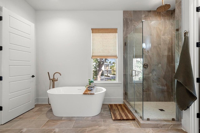 full bath featuring baseboards, a soaking tub, and a shower stall