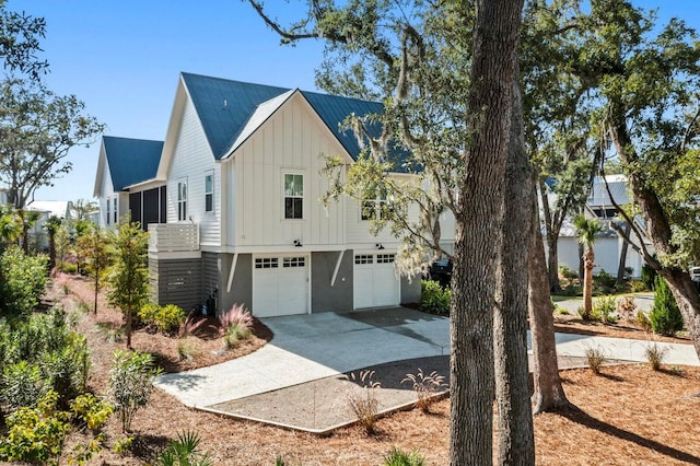 view of property exterior with an attached garage, board and batten siding, driveway, and metal roof