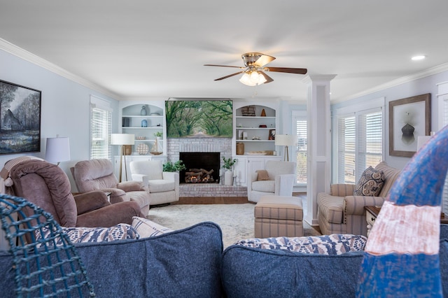 living room featuring ornate columns, crown molding, a fireplace, and a wealth of natural light