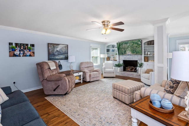 living room with a fireplace, wood finished floors, a ceiling fan, baseboards, and ornamental molding