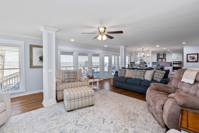 living room with crown molding, ornate columns, a ceiling fan, wood finished floors, and baseboards