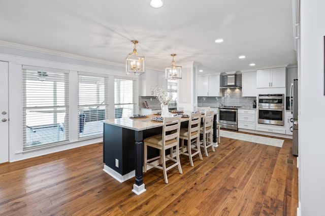 kitchen featuring hardwood / wood-style flooring, a kitchen island, white cabinets, appliances with stainless steel finishes, and backsplash