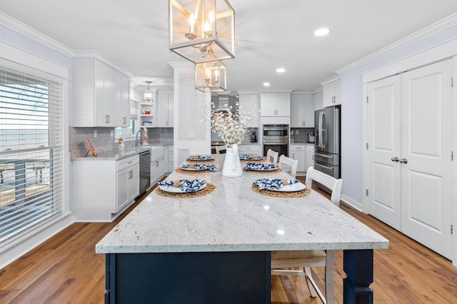 kitchen featuring appliances with stainless steel finishes, wood finished floors, white cabinetry, and crown molding