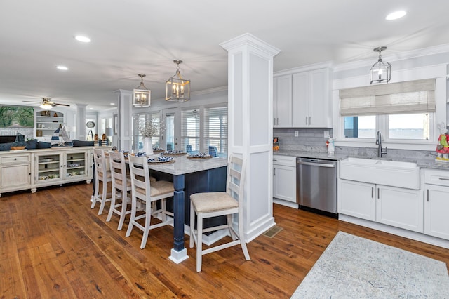 kitchen with a sink, a wealth of natural light, decorative columns, and stainless steel dishwasher