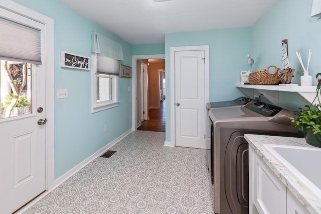 clothes washing area featuring laundry area, a wealth of natural light, washing machine and clothes dryer, and visible vents