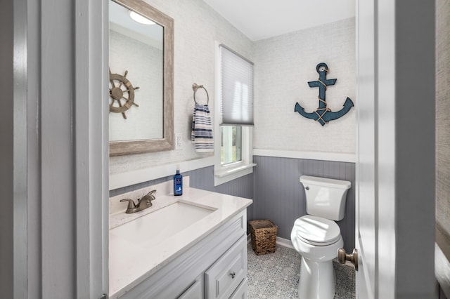 half bathroom with toilet, a wainscoted wall, and vanity