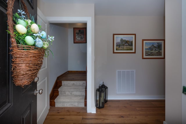 stairway featuring visible vents, baseboards, and wood finished floors