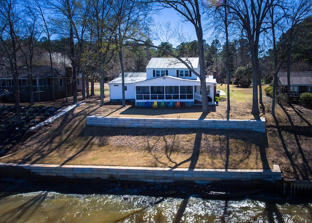 back of property with a water view and a sunroom