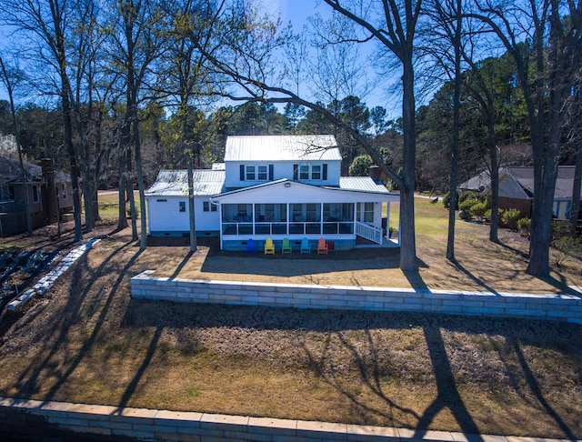 view of front of property with a front yard, a sunroom, metal roof, and crawl space