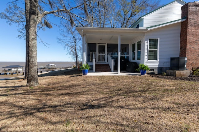 rear view of house featuring a sunroom, central AC, a lawn, and a chimney