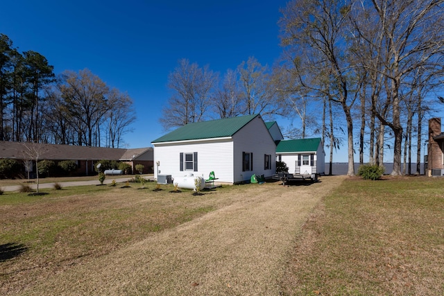 exterior space with metal roof, driveway, and a lawn