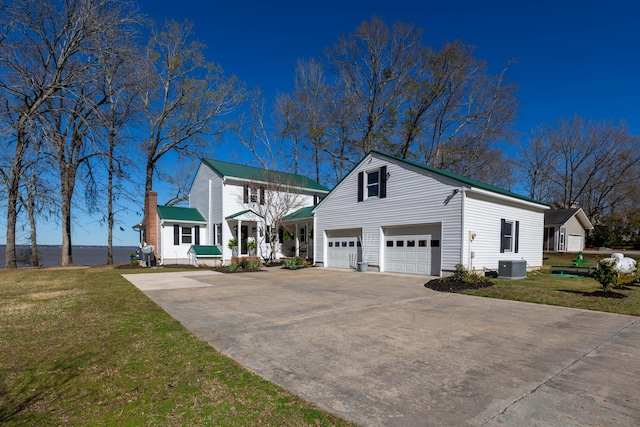 view of front of home featuring a front yard, metal roof, a garage, cooling unit, and driveway