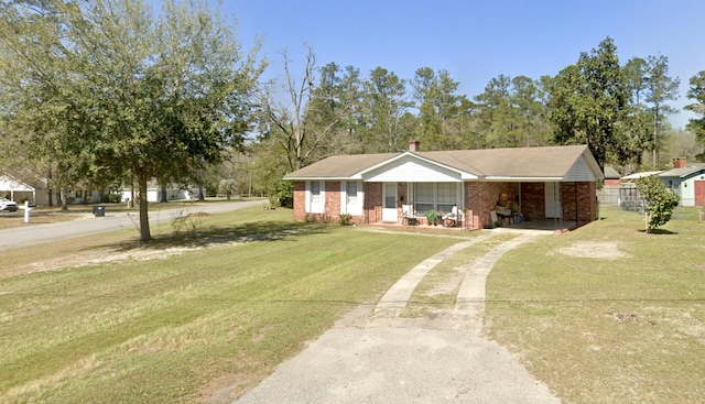 ranch-style house with a front yard, an attached carport, covered porch, driveway, and brick siding