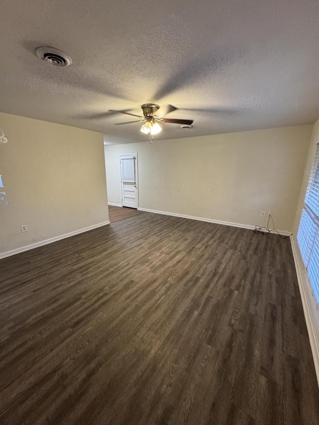 spare room with dark wood-style flooring, ceiling fan, visible vents, baseboards, and a textured ceiling