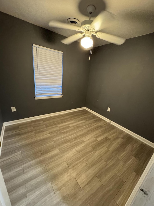 empty room with baseboards, wood finished floors, and a ceiling fan