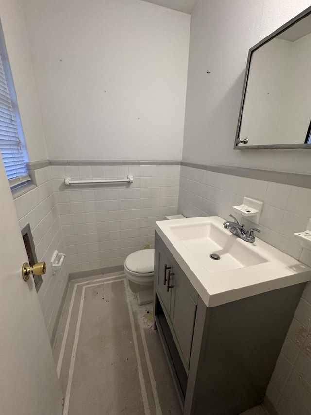 bathroom featuring toilet, a wainscoted wall, tile walls, and vanity