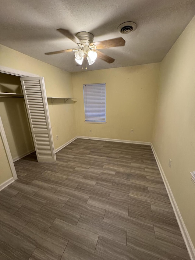 unfurnished bedroom with a closet, ceiling fan, visible vents, baseboards, and a textured ceiling