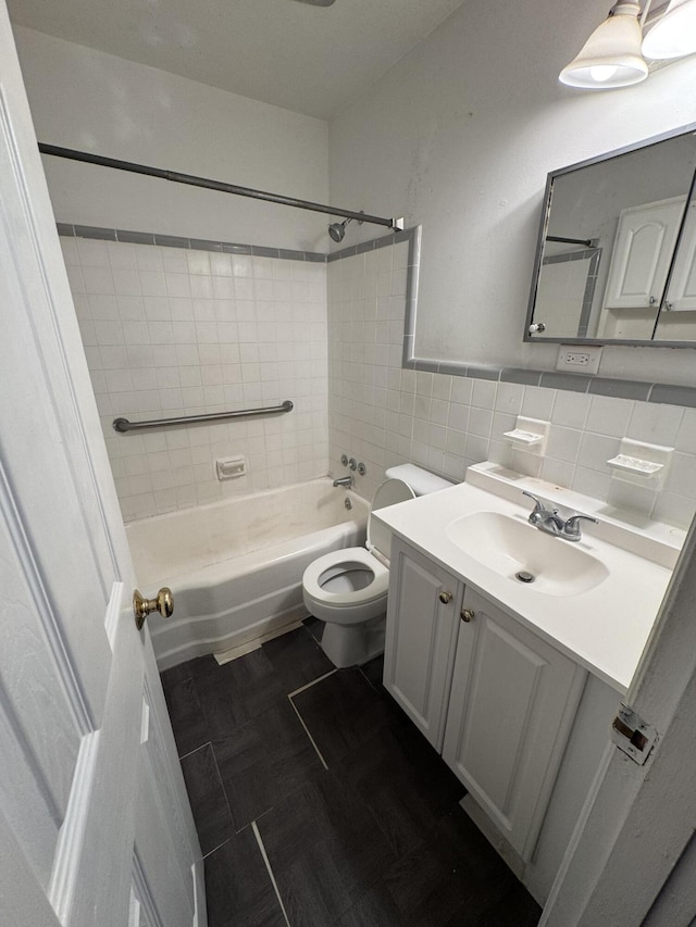 bathroom with tile walls, toilet, bathtub / shower combination, and vanity