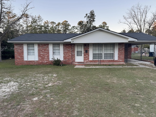 view of front of home with brick siding, a carport, and a front yard